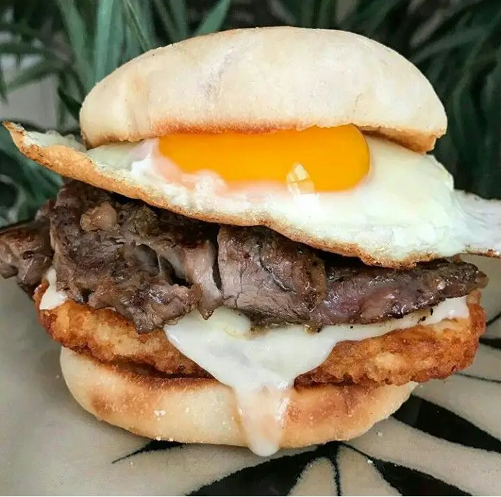 Sandwich with hashbrowns, cheese, ribeye steak, and an egg